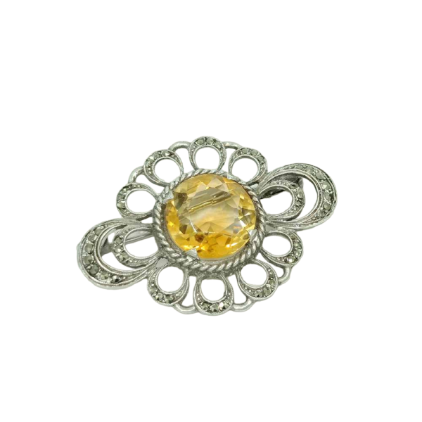 Broche en argent poli ornée d'une citrine jaune intense et de marcassites scintillantes, avec un motif ajouré élégant et raffiné.